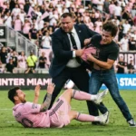 Um jogador de futebol vestindo a camisa rosa do Inter Miami caído de costas no gramado